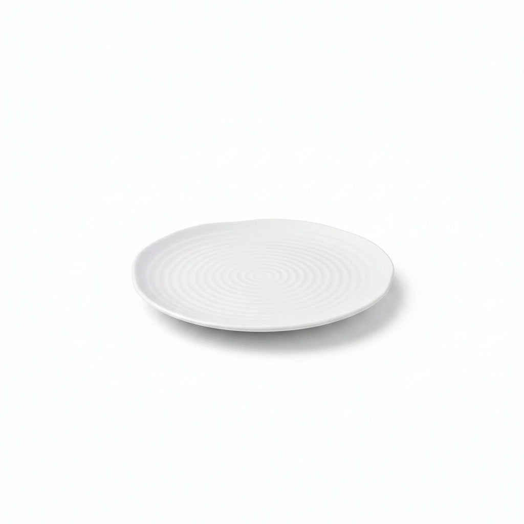 A round white ceramic plate with a textured concentric spiral pattern, shown from a top-down angle on a white background.